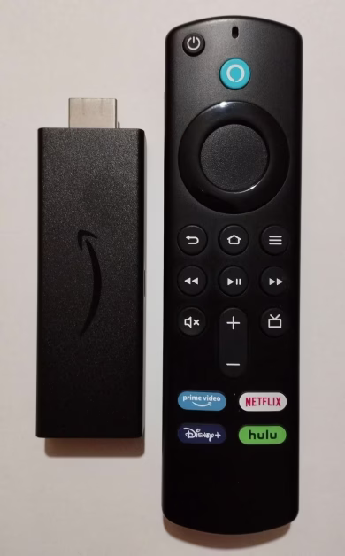 Clé de streaming HDMI Amazon Fire TV Stick et sa télécommande vocale disposées de biais sur un fond blanc épuré.