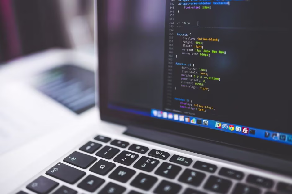 Écran d'ordinateur portable affichant des lignes de code informatique multicolores avec le clavier au premier plan.