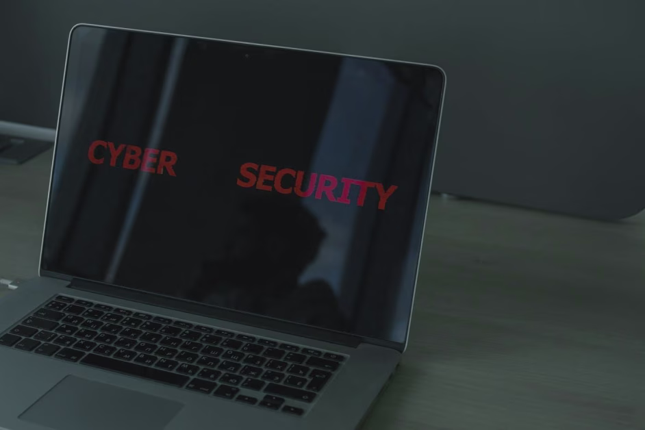 Ordinateur portable ouvert sur un bureau affichant le texte "CYBER SECURITY" en lettres rouges sur fond noir.