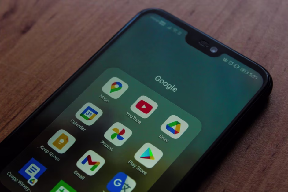 Gros plan incliné sur l'écran d'un smartphone Android affichant un dossier avec les icônes des applications Google.