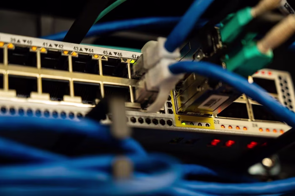 Gros plan sur un commutateur réseau ou switch de serveurs avec plusieurs câbles Ethernet bleus branchés dans les ports RJ45.