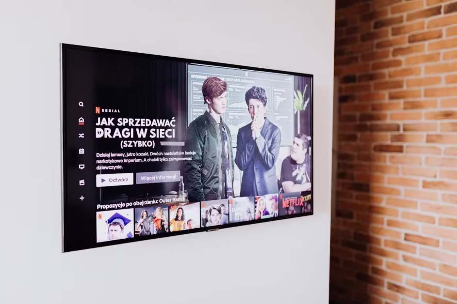 Écran de télévision plat fixé sur un mur blanc, affichant la page de présentation d'une série sur l'interface Netflix.